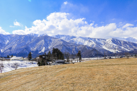 Hakuba mountain range  and  Hakuba village houses  in the winter with snow on the mountain and blue sky and clouds background in Hakuba  Nagano Japan.の写真素材