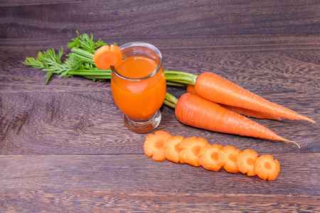 Healthy eating and dieting concept,fresh carrot  and carrot juice or organic healthy juice in glass ,  on a grey wooden table wall background with copy space .の写真素材