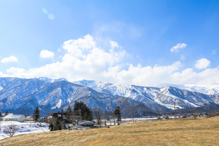 Hakuba mountain range  and  Hakuba village houses  in the winter with snow on the mountain and blue sky and clouds background in Hakuba  Nagano Japan.の写真素材