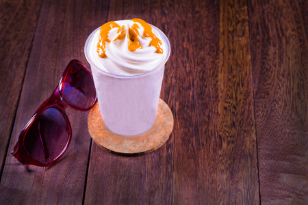 Chocolate ice cream in a cup and sunglasses on a grey wooden table wall background with copy space .の写真素材