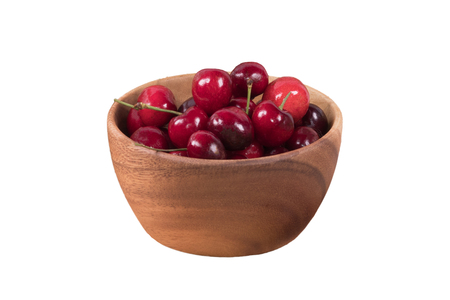 Red cherries in wooden bowl isolated on white background with clipping path.の写真素材