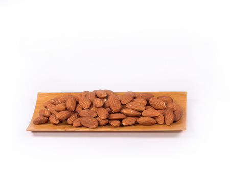 Almond nuts in wooden bowl isolated on white background with clipping path.の写真素材