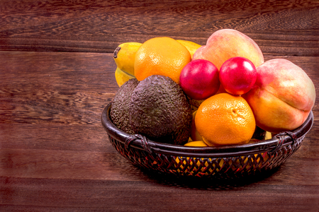Fresh organic fruits in wicker basket on a grey wooden table wall background with copy space .の写真素材