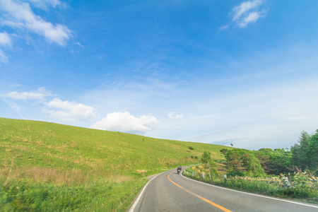 Beautiful landscape view of a country road and green grass with blue sky backgroundの写真素材