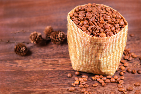 Coffee beans in a bag on wooden background with copy space .の写真素材
