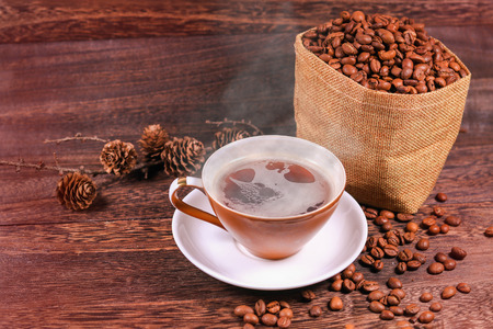 Cup of black coffee and coffee beans in a bag on wooden background with copy space .の写真素材