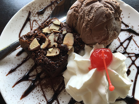 brownie cake and chocolate icecream with cheery on cream on white dishの写真素材