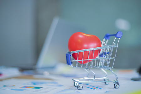 red heart in shopping cart on wooden table, shopping conceptの写真素材