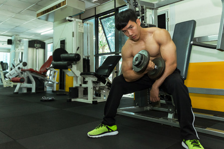 Fitness man in training showing exercises with dumbbells in gym, fitness concept, sport conceptのeditorial素材