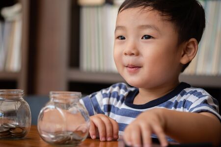 cute boy putting money coins in glass,saving money concept