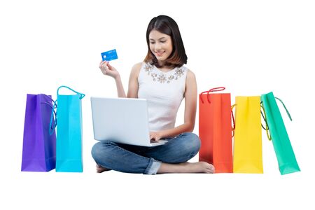 Happy woman in summer enjoying shopping holding credit card and colorful shopping bag on white background, shopping concept, isolate conceptの写真素材