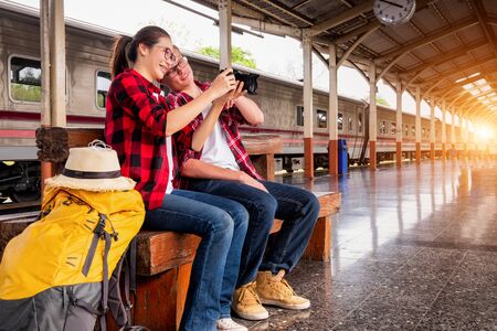 Happy young coupleÂ travellers together on vacation taking a photo at the train station, travel concept, couple conceptの写真素材