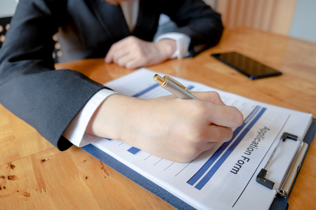 young woman sitting for candidate at job interview and writing resume on application form in office, job interview, interview conceptの写真素材