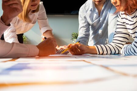 Businesspeople analyzing investment graph meeting brainstorming and discussing plan in meeting room,...