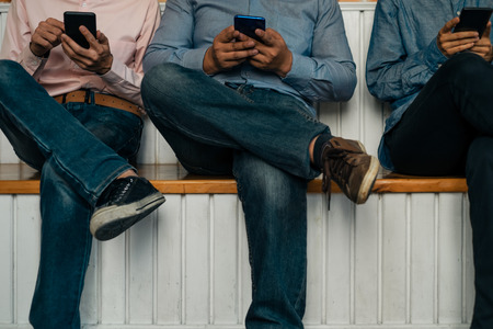 Young business people using smartphone on wooden table share data and send messages in groups,...