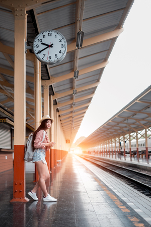 Smiling woman traveler with backpack holding vintage camera on holiday relaxation at the train station,relaxation concept, travel conceptの写真素材
