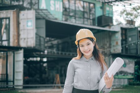 young engineers wearing helmat looking camera holding blueprint modern project outside the office, Engineer conceptの写真素材