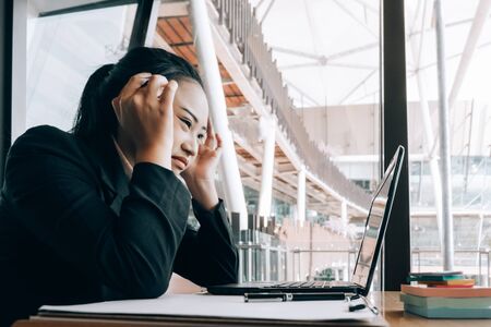 young business woman sitting at table in office feeling tired and stressed when investment loss, investment concept, success conceptの写真素材
