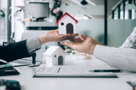 Real estate agents holding model house and give for customers with sale contract,real estate concept.の写真素材