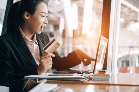 beautiful woman holding credit card and using laptop and smartphone shopping website online, shopping conceptの写真素材