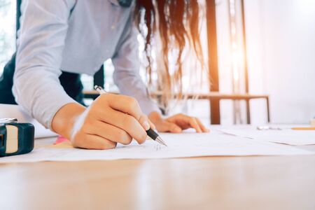 engineers pointing to building on blueprint to drawing design building Project in office,...