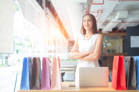 beautiful woman standing arms crossed shopping bags looking at camera, shopping conceptの写真素材