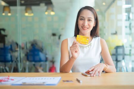 beautiful woman holding credit card enjoying in shopping looking at camera, shopping conceptの写真素材