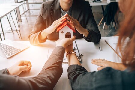 Real estate agents holding model house and give for customers with sale contract,real estate concept.の写真素材