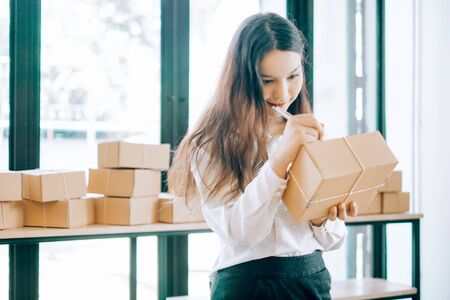 happy women write the name and address of the customer to send through the shipping company, online business concept, business owner conceptの写真素材