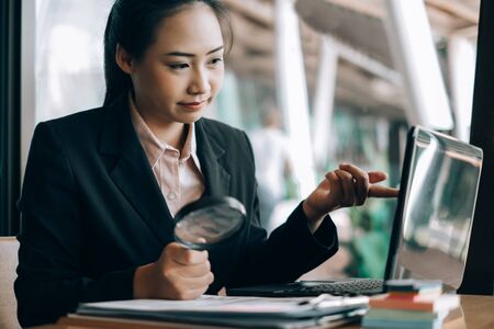 business woman smiling using a magnifying glass search analyzing investment graph at the office, investment conceptの写真素材