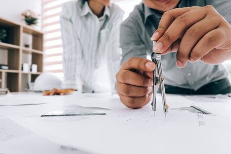 engineers pointing to building on blueprint to drawing design building Project in office, construction concept. Engineer conceptの写真素材