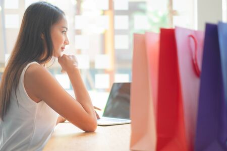 beautiful woman using laptop enjoying shopping website online with shopping bags, shopping conceptの写真素材