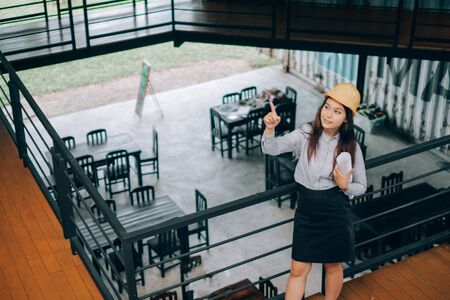 young engineers wearing helmat looking up holding blueprint modern project in the office, Engineer conceptの写真素材