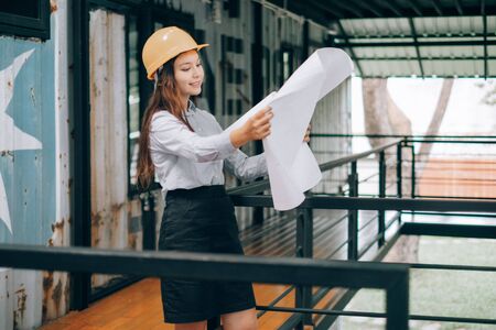 young engineers wearing helmat looking up holding blueprint modern project in the office, Engineer conceptの写真素材