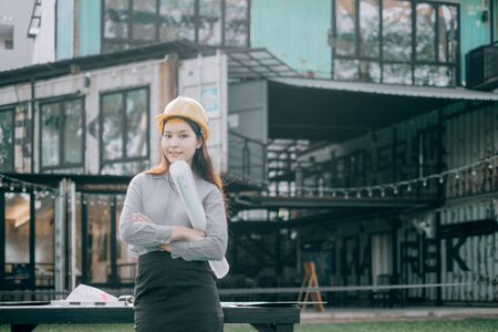 young engineers wearing helmat looking camera holding blueprint modern project outside the office, Engineer conceptの写真素材
