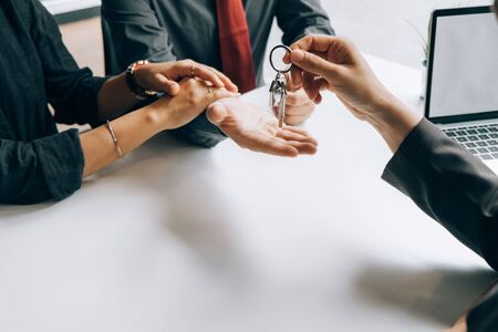 Real estate agents holding model house and keys for submit documents for customers to sign for a...
