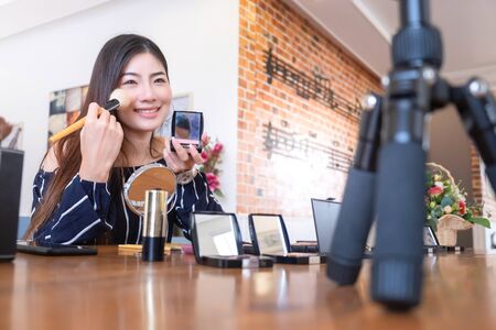 Happy girl blogger at cafe talking about makeup and beauty and recording video tutorial for internet, blogger conceptの写真素材