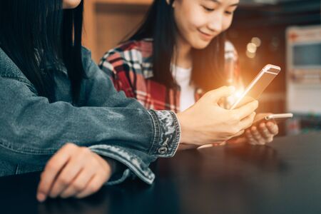 young student sitting in library using smartphone on wooden table share data and send messages, technology conceptの写真素材