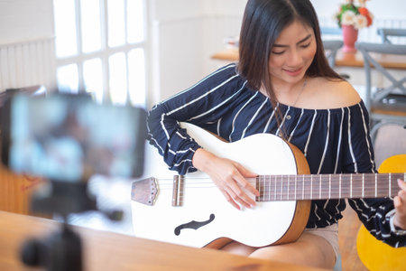 Happy girl blogger at cafe live guitar on broadcasts website for viewers to see through, blogger conceptの写真素材