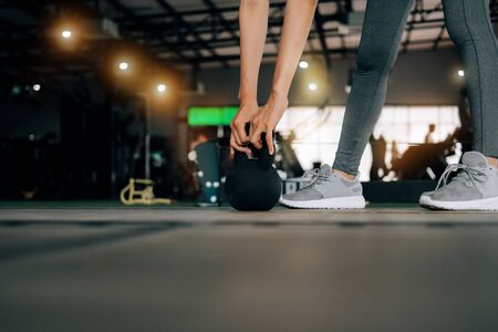 sport woman at fitness gym club doing exercise for arms with kettlebell and showing muscle bodybuilding, fitness concept, sport conceptの写真素材