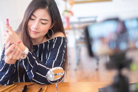 Happy girl blogger at cafe talking about makeup and beauty and recording video tutorial for internet, blogger conceptの写真素材