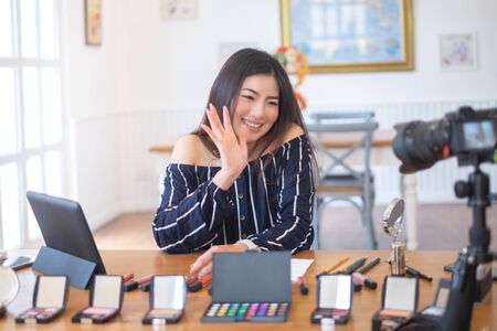 Happy girl blogger at cafe talking about makeup and beauty and recording video tutorial for internet, blogger conceptの写真素材