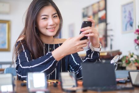 Happy girl blogger at cafe talking about makeup and beauty and recording video tutorial for internet, blogger conceptの写真素材