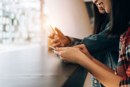 young student sitting in library using smartphone on wooden table share data and send messages, technology conceptの写真素材