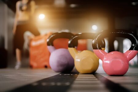 kettlebell in front of sport woman at fitness gym club doing exercise for arms with dumbbells, fitness concept, sport conceptの写真素材