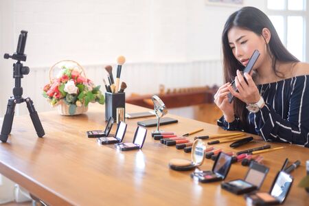 Happy girl blogger at cafe talking about makeup and beauty and recording video tutorial for internet, blogger conceptの写真素材