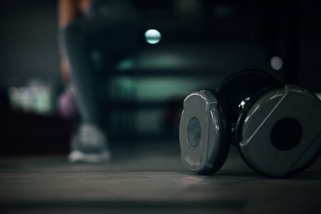 dumbbells in front of sport woman at fitness gym club doing exercise for arms with kettlebell,...