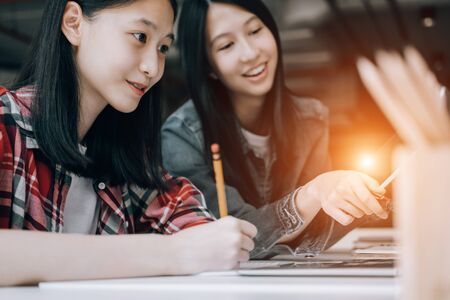 young student sitting in library college studying and sharing knowledge with laptop together, education conceptの写真素材