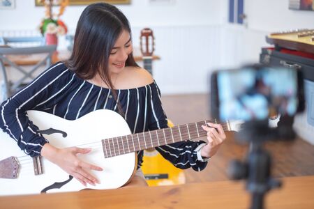 Happy girl blogger at cafe live guitar on broadcasts website for viewers to see through, blogger conceptの写真素材