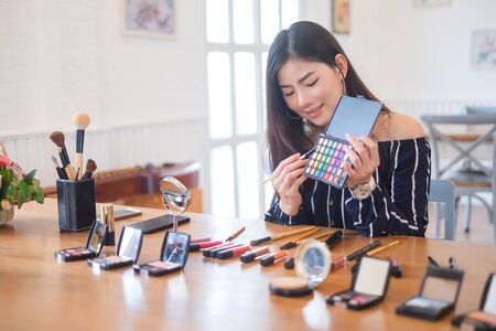 Happy girl blogger at cafe talking about makeup and beauty and recording video tutorial for internet, blogger conceptの写真素材